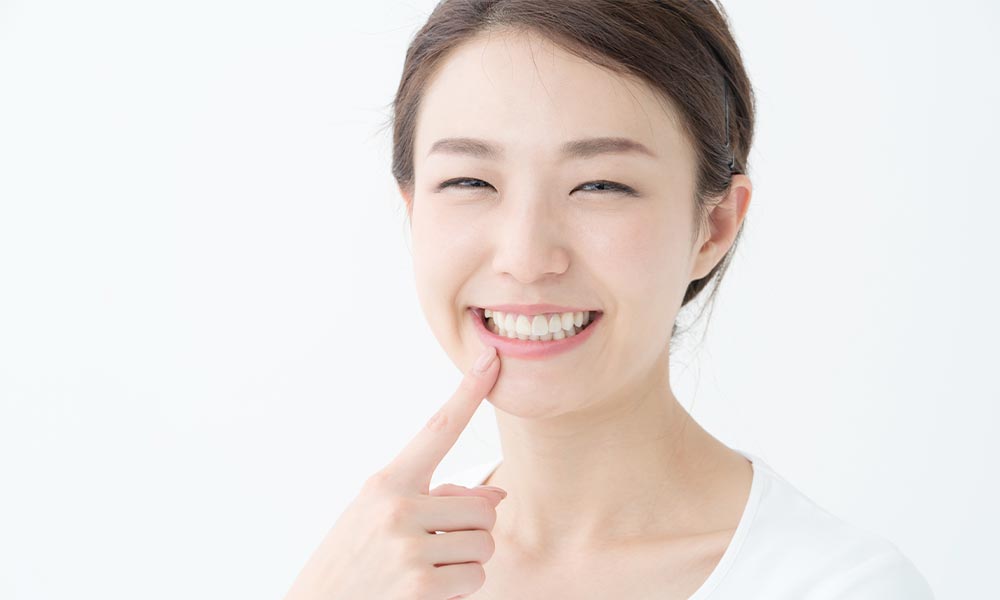 歯を指さす女性の画像